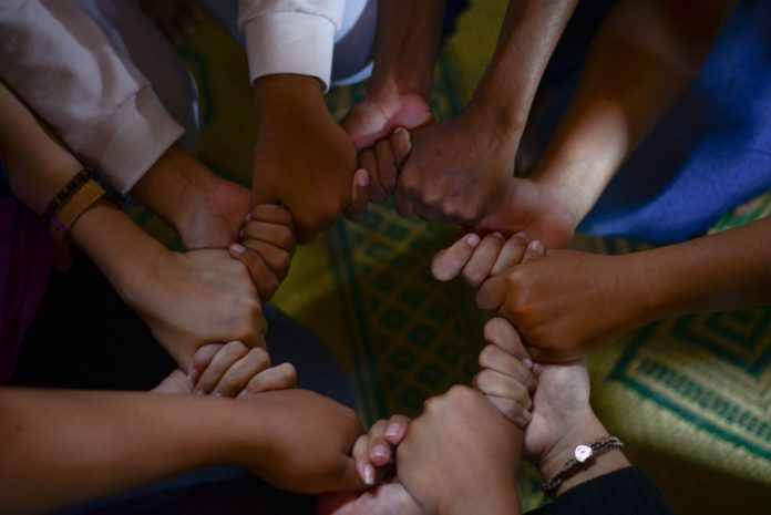Image depicts interlocking hands to signify how UC empowers employees to communicate and collaborate effectively
