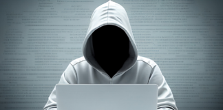 Anonymous hacker with white hoodie typing computer laptop.
