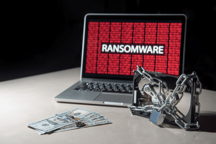 Laptop infected by ransomware and a locked harddrive near money with a key on top.