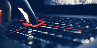 Index finger pressing a key on laptop keyboard with a targeting reticle.
